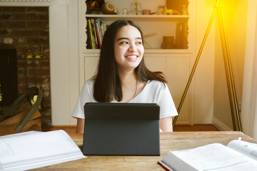 Young female student smiles as she studies during learning from home